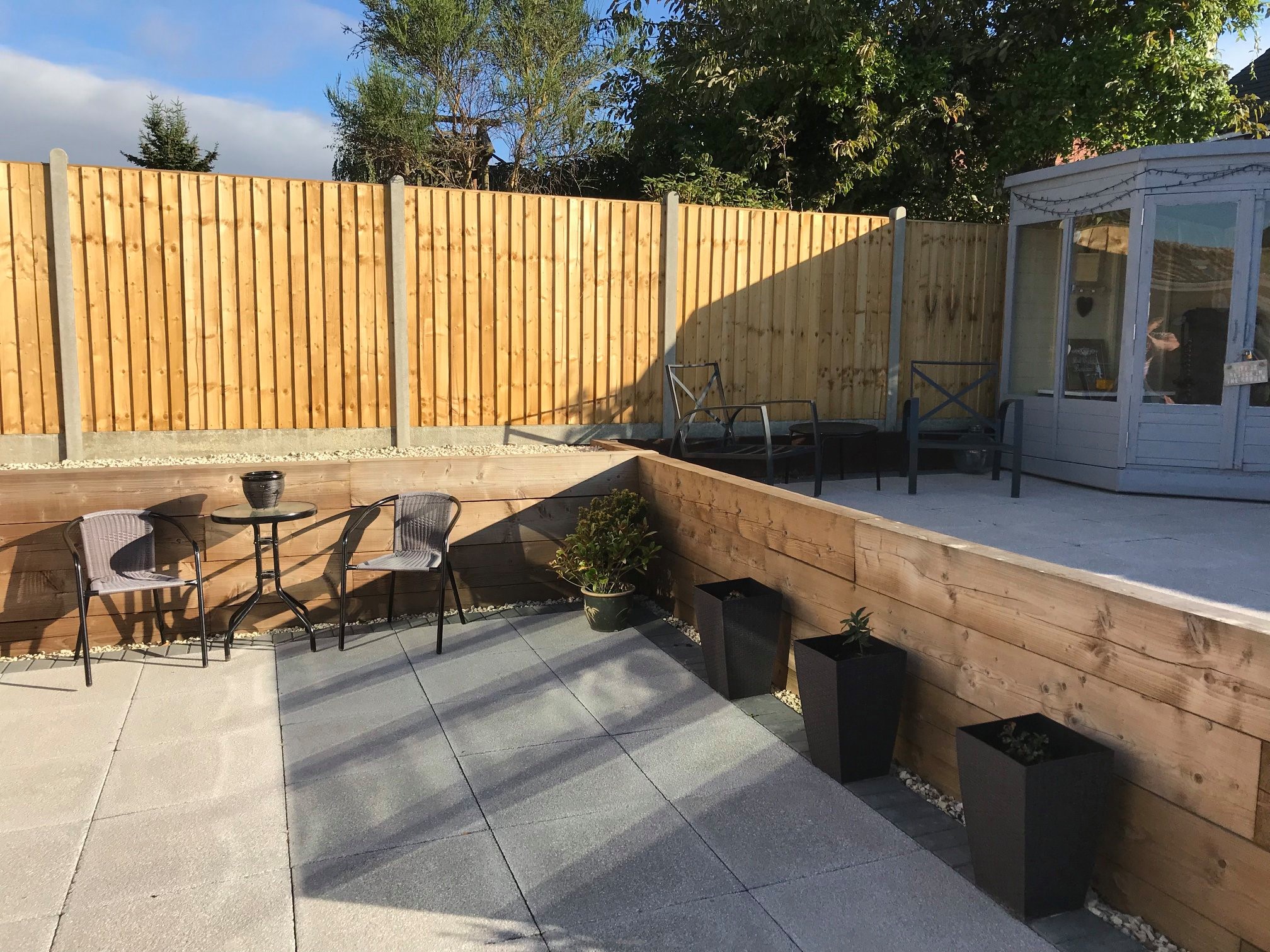 Garden with close board fencing, sleeper beds and a paved patio